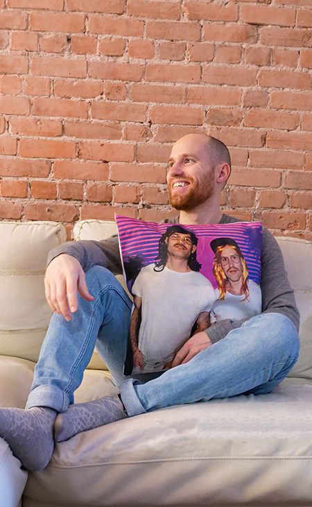 Man on couch holding a custom printed cotton canvas pillow